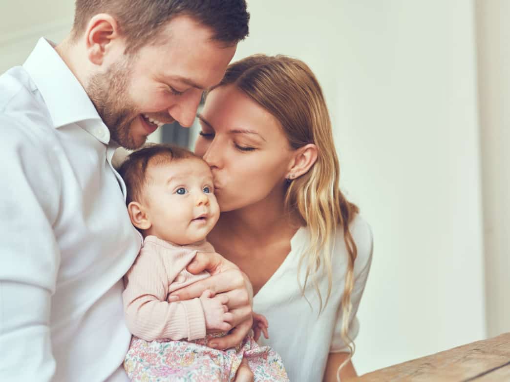 New parents holding baby representing 5 powerful parenting tips.