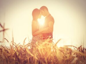 couple snuggling in field at sunset representing Free Relationship Advice From A Marriage Counselor