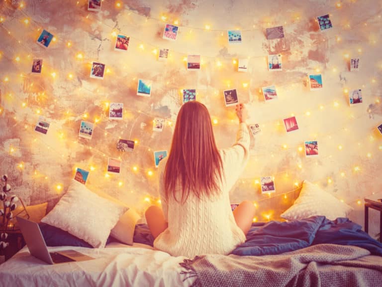 Woman looking at a wall of photos, reminiscing representing Why You Can't Stop Thinking About Your Ex