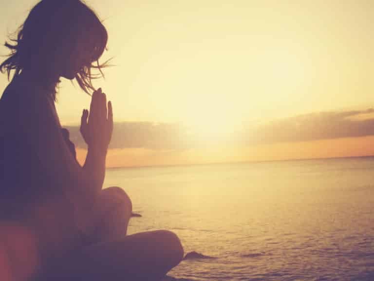 Woman meditating with a beautiful sunset in the background. Living in a beautiful state.