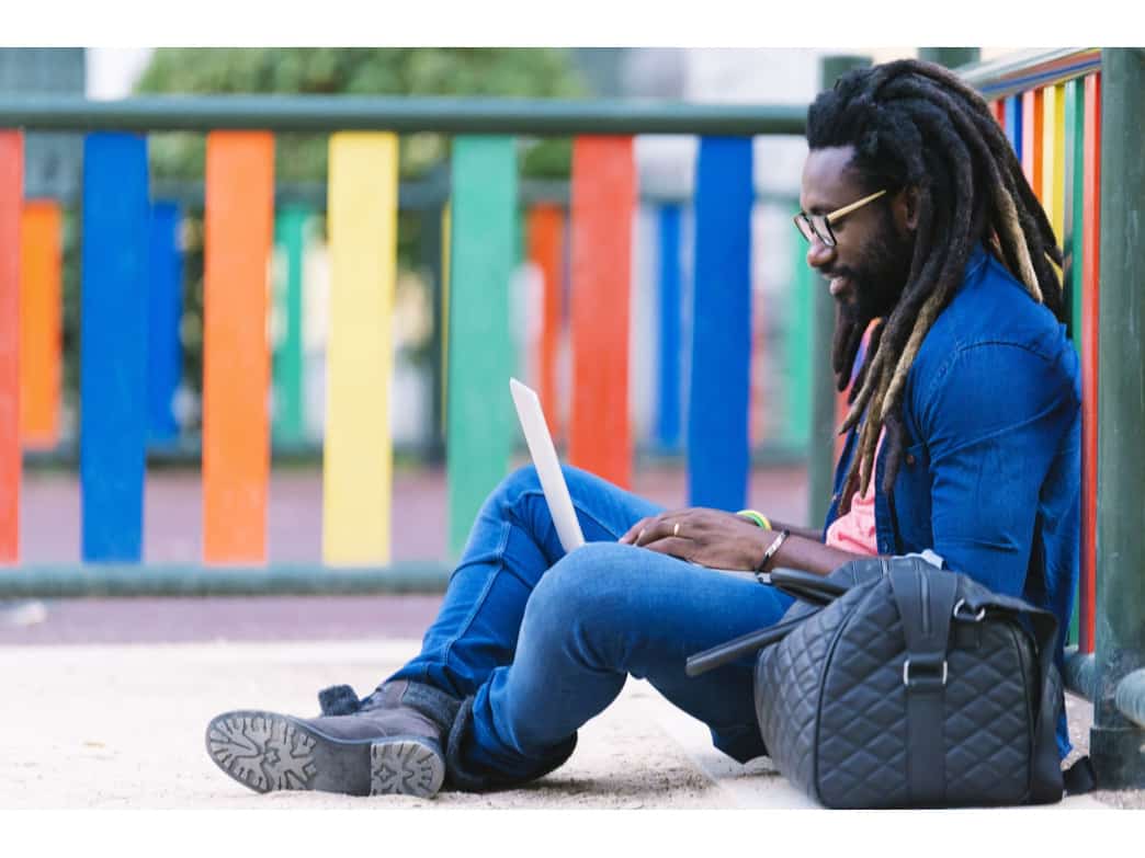 Man sitting outside on his laptop. Four benefits of online coaching.