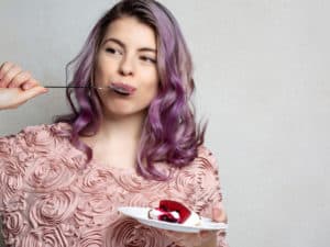 Woman eating a slice of cake representing Do You Have An Unhealthy Relationship with Food?