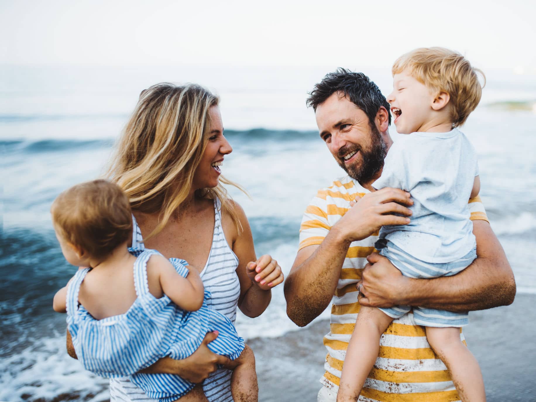 Mother and father each holding a child representing Coparenting Together.