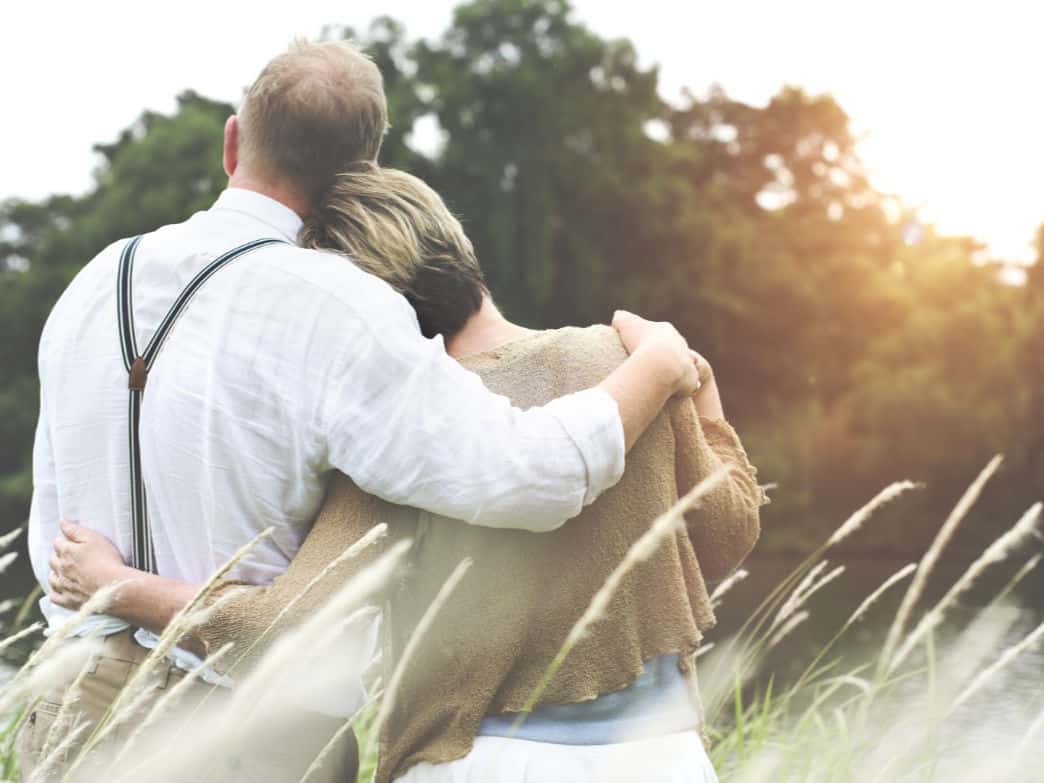 Man and woman with their arms around each other, staring into the distance. How to fall back in love with your spouse.