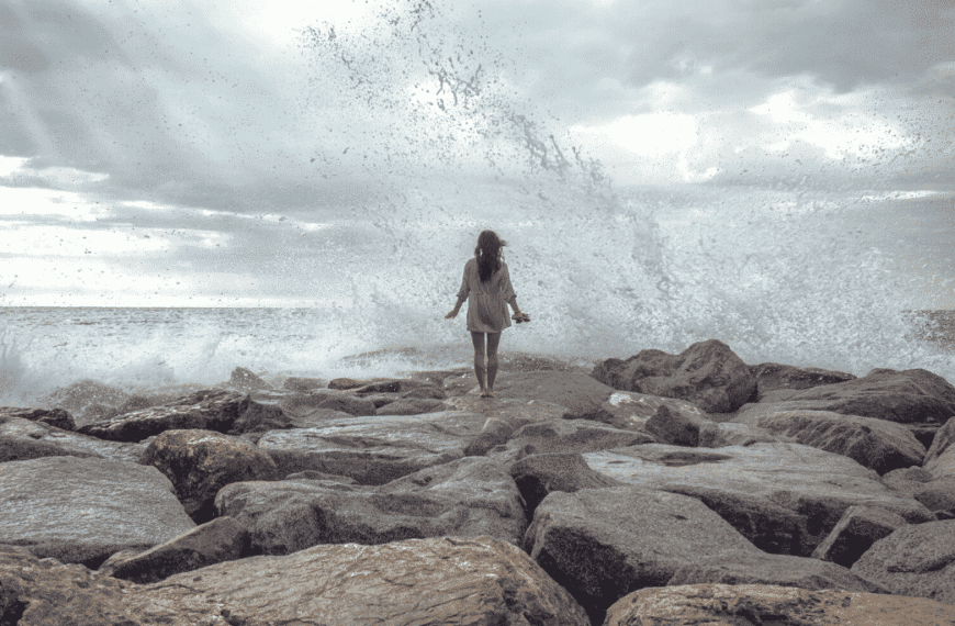 Woman going towards big crashing waves. Resilience In The Face Of Chaos.