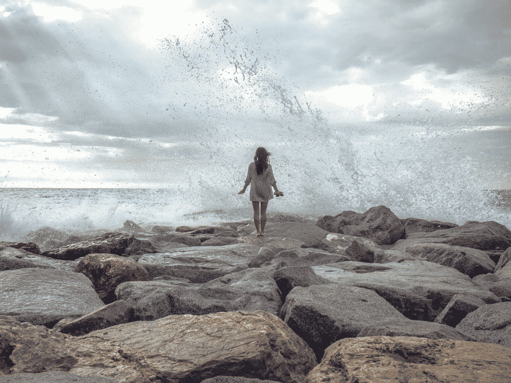 Woman going towards big crashing waves. Resilience In The Face Of Chaos.