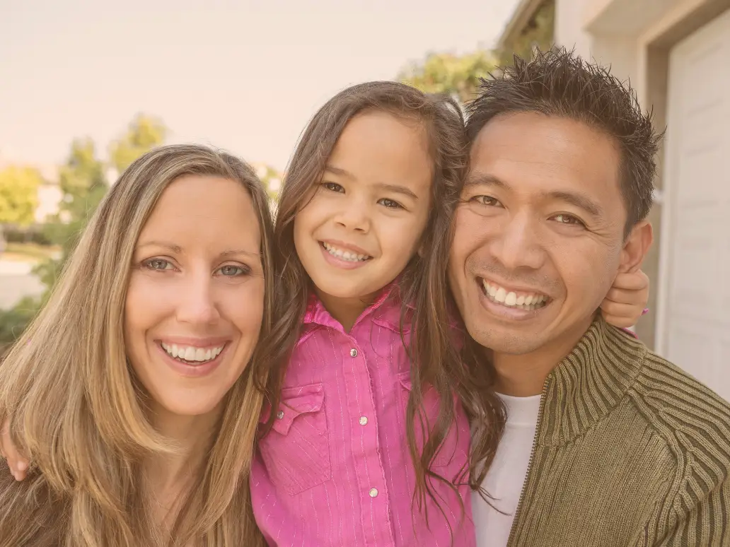 Mother, father, and daughter in the middle, all smiling representing Love without Borders: Cross-Cultural Relationships