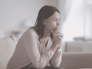 Women sitting on couch, deep in thought representing When To Call It Quits In a Relationship