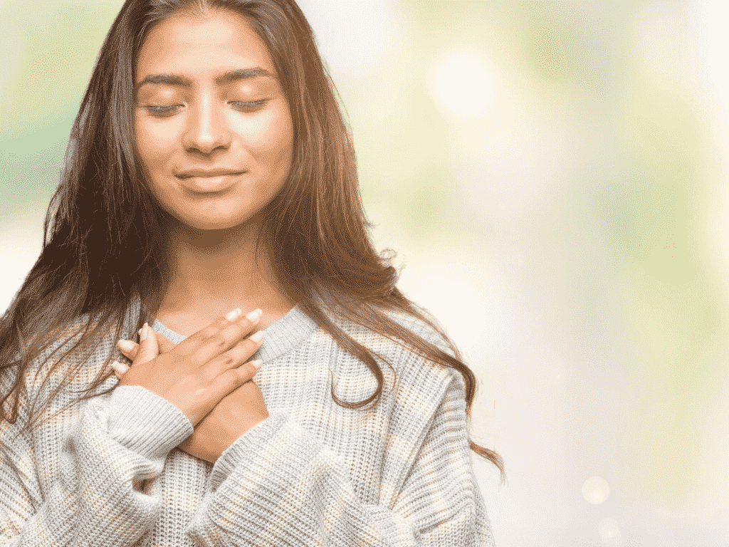 Woman with hands over heart looking satisfied and happy representing being honest with yourself.