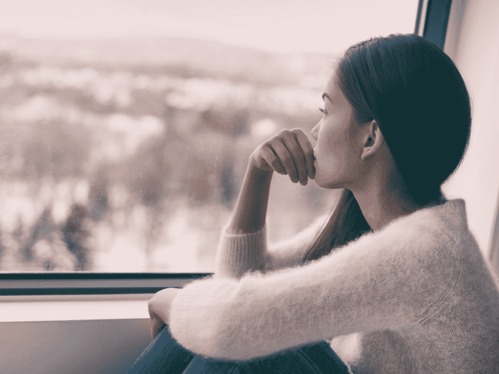 Woman looking out the window representing Navigating the Post-Divorce Stages of Grief