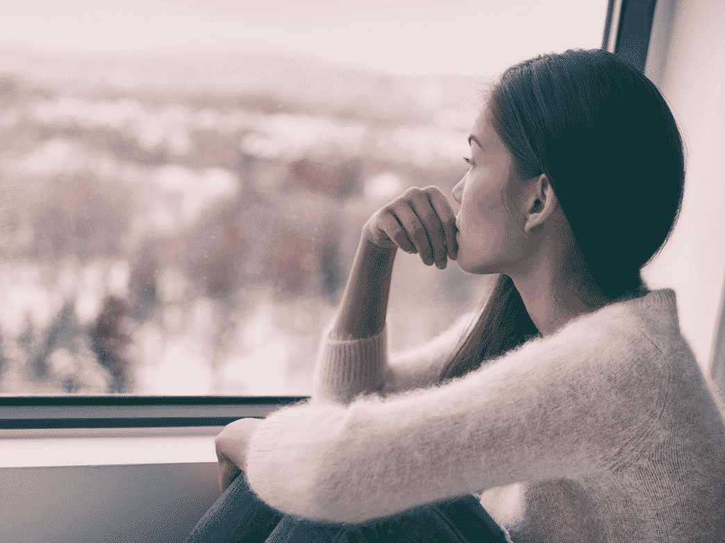 Woman looking out the window representing Navigating the Post-Divorce Stages of Grief