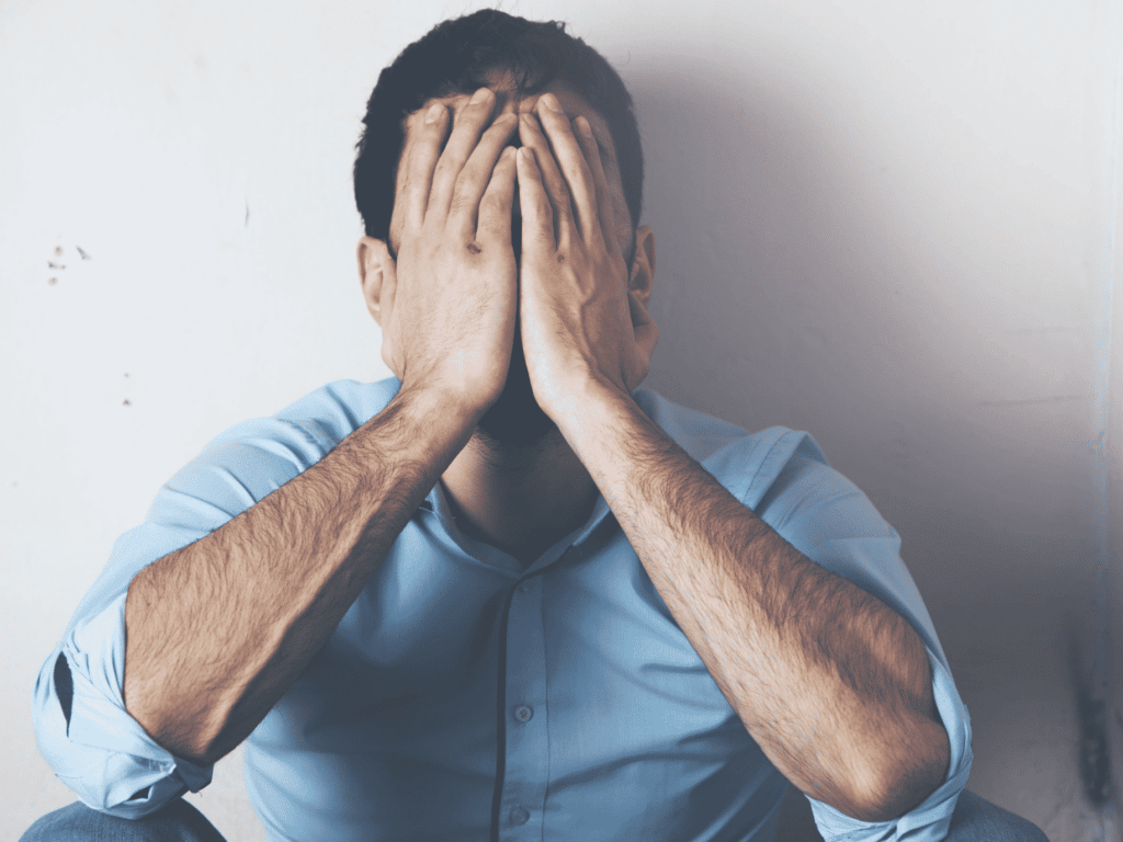 man sitting on floor with face in hands representing healing toxic shame