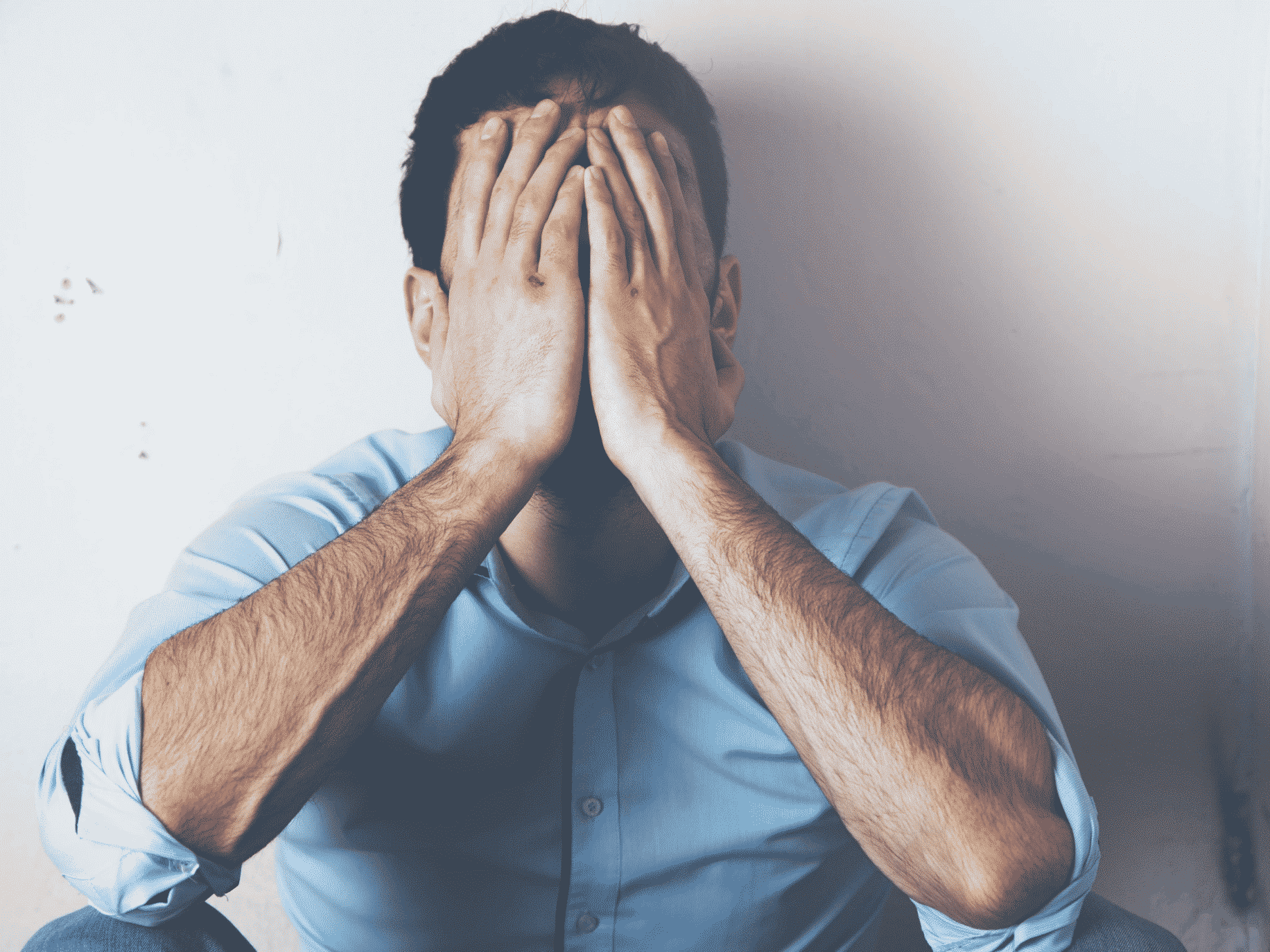 man sitting on floor with face in hands representing healing toxic shame