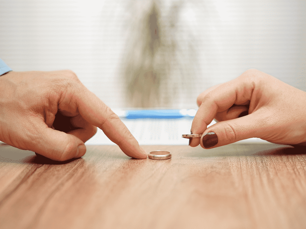 Weddings rings taken off the hands and on the table representing Amicable divorce.