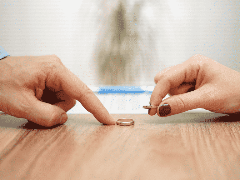 Weddings rings taken off the hands and on the table representing Amicable divorce.