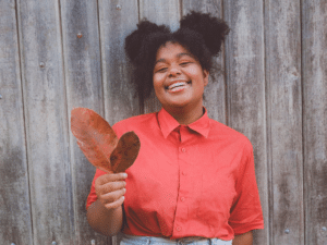 Woman smiling and holding two leaves representing Radical Self Acceptance