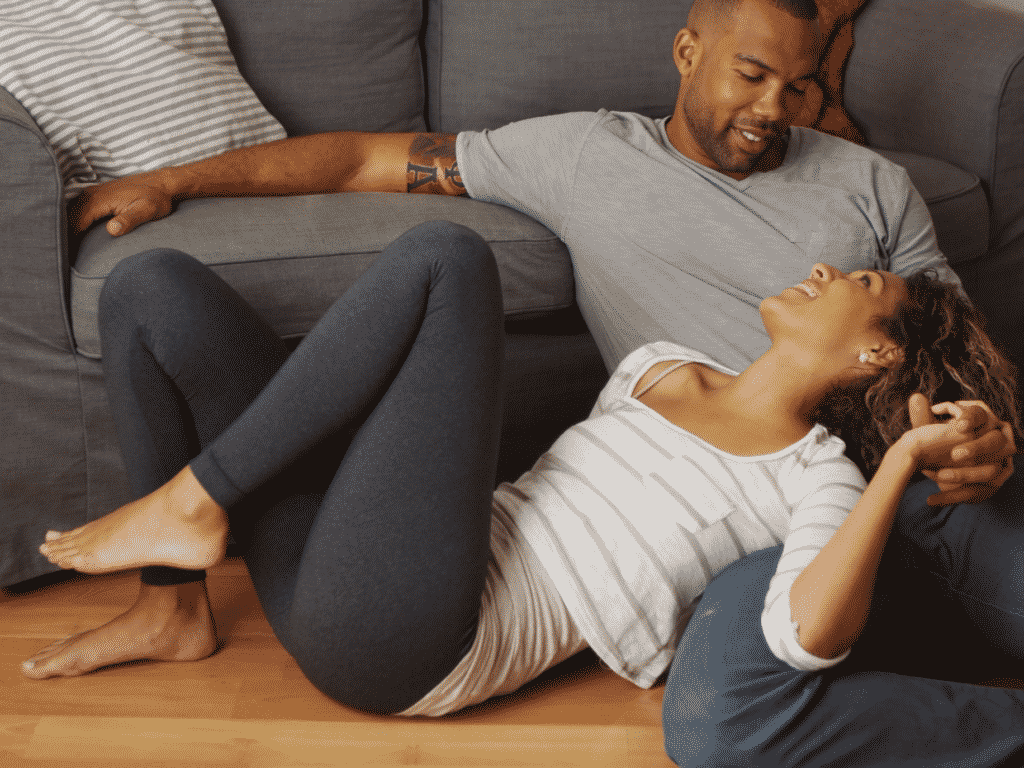 Couple cuddled up next to couch representing emotional intimacy through couples counseling
