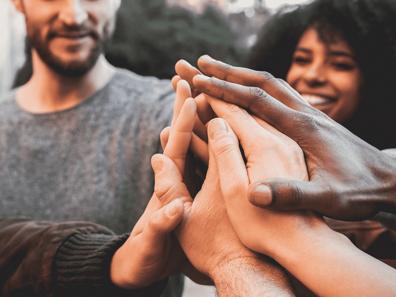 Group of people with hands together in the middle. Practicing Intellectual Humility to Improve Your Relationships.