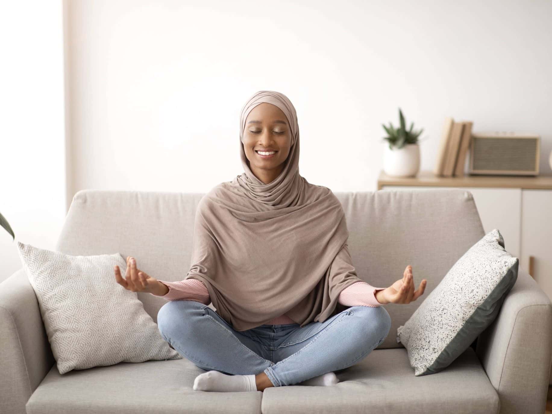 Woman meditating on couch representing 3 Stress Management Techniques for Chaotic Times