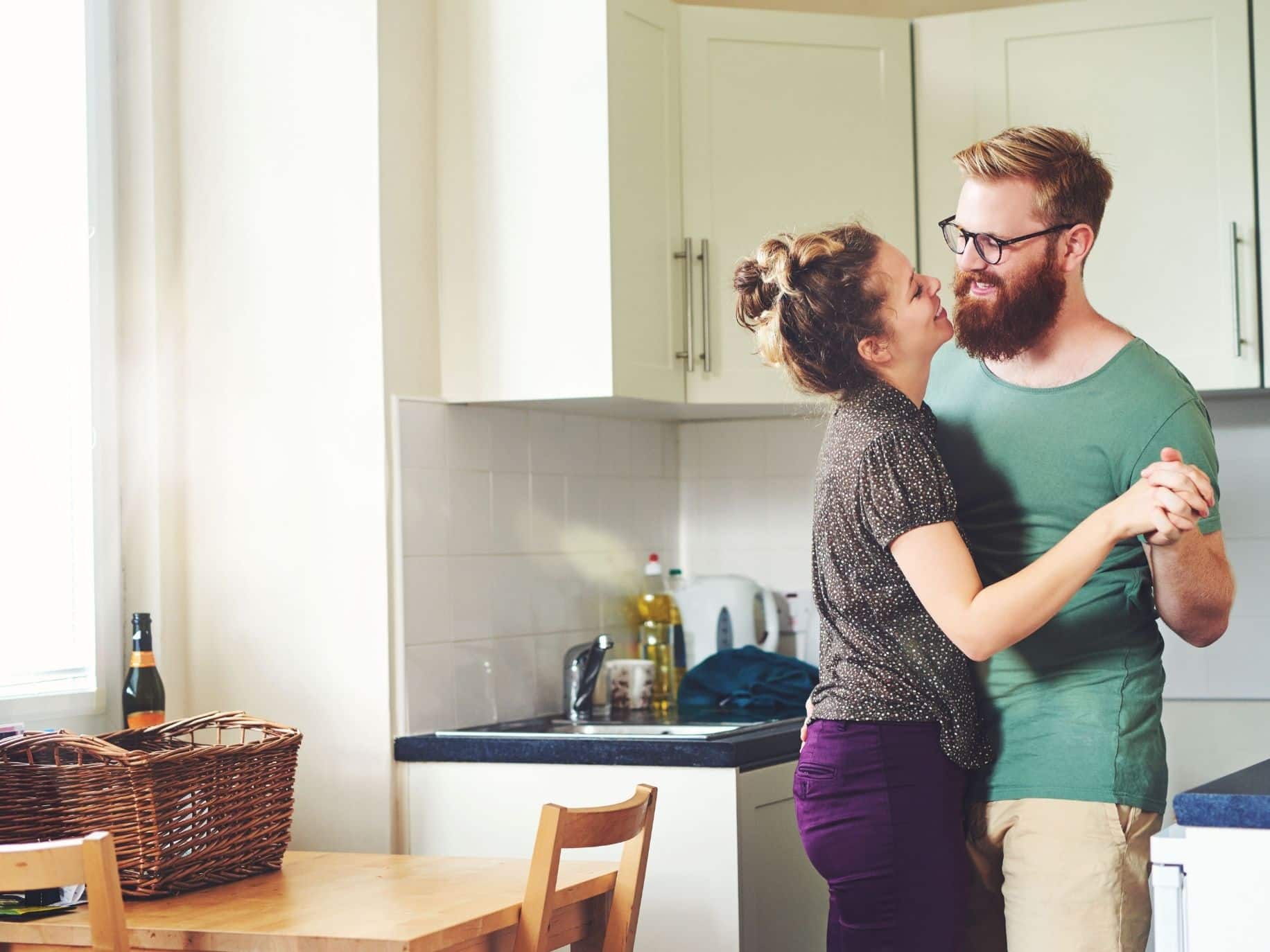 Couple embracing in the kitchen representing Rethinking Date Night: The Micro-Date