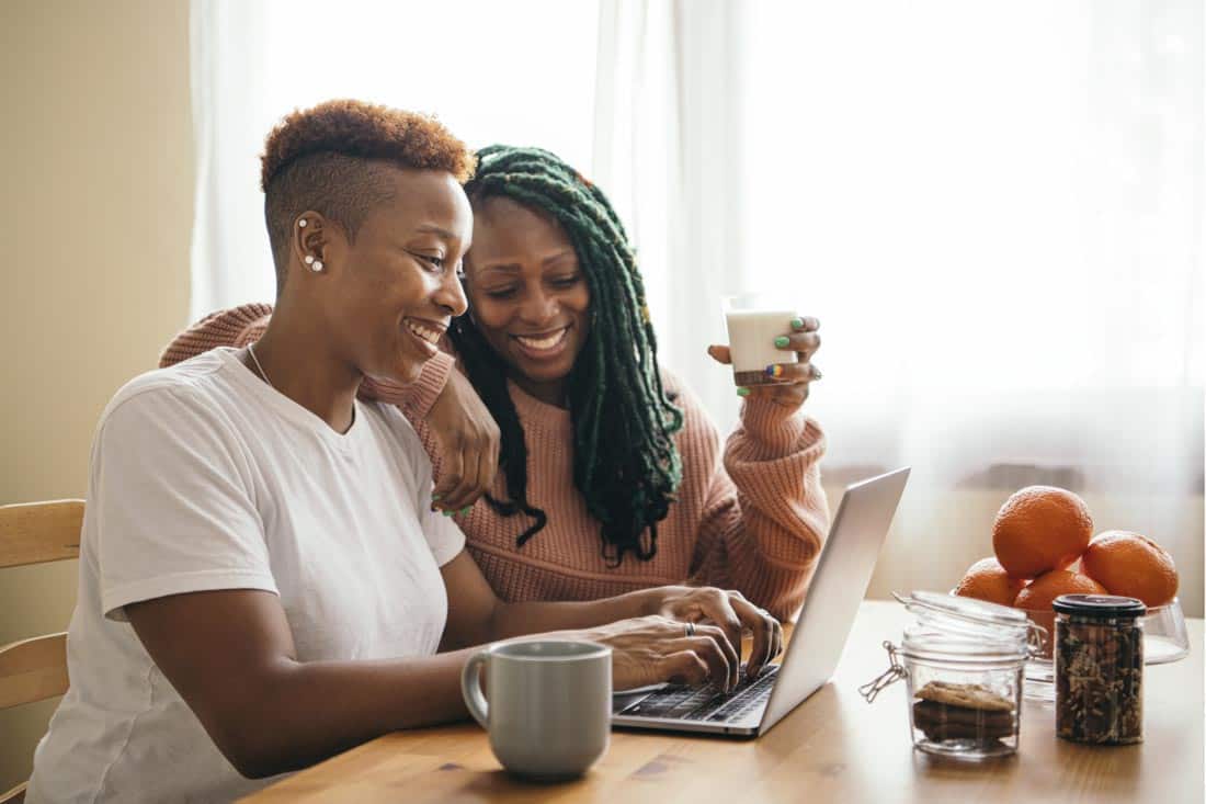 Two African American women working on laptop together at table