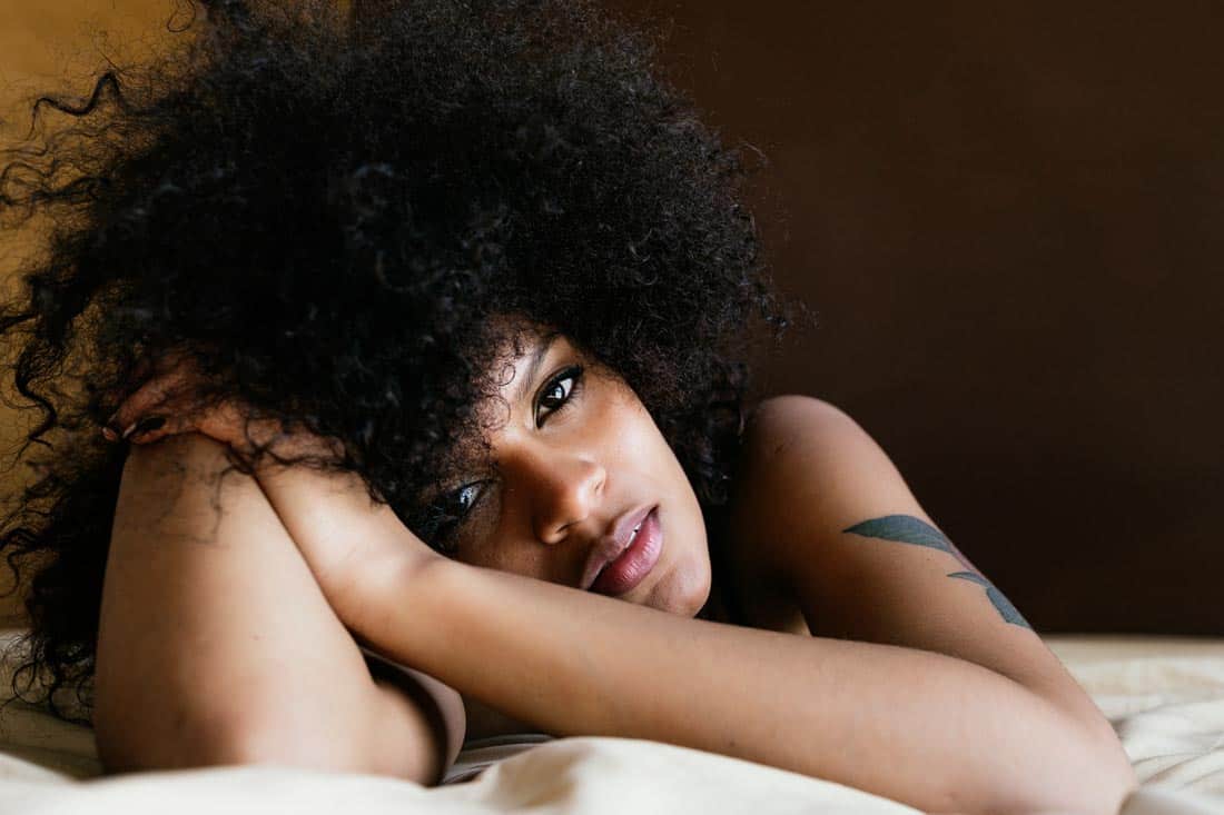 African American woman lying down in bed and resting her head on her arm.