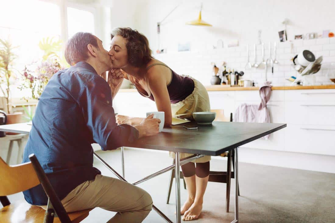 Couple kissing at kitchen table