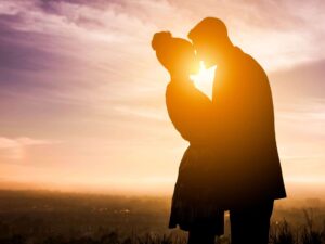 Couple embracing with a beautiful sunset in the background. How premarital counseling works.