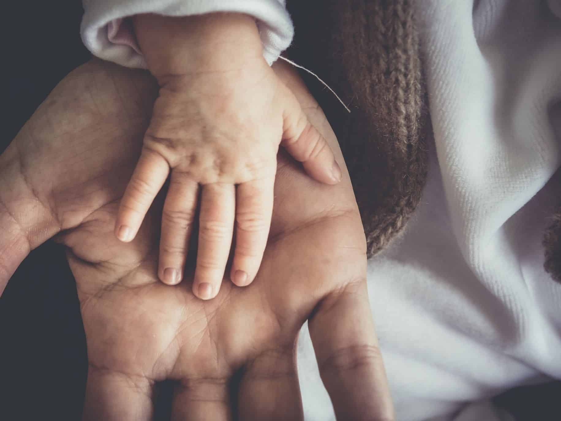 Baby's hand on top of father's hand representing Preparing for fatherhood.