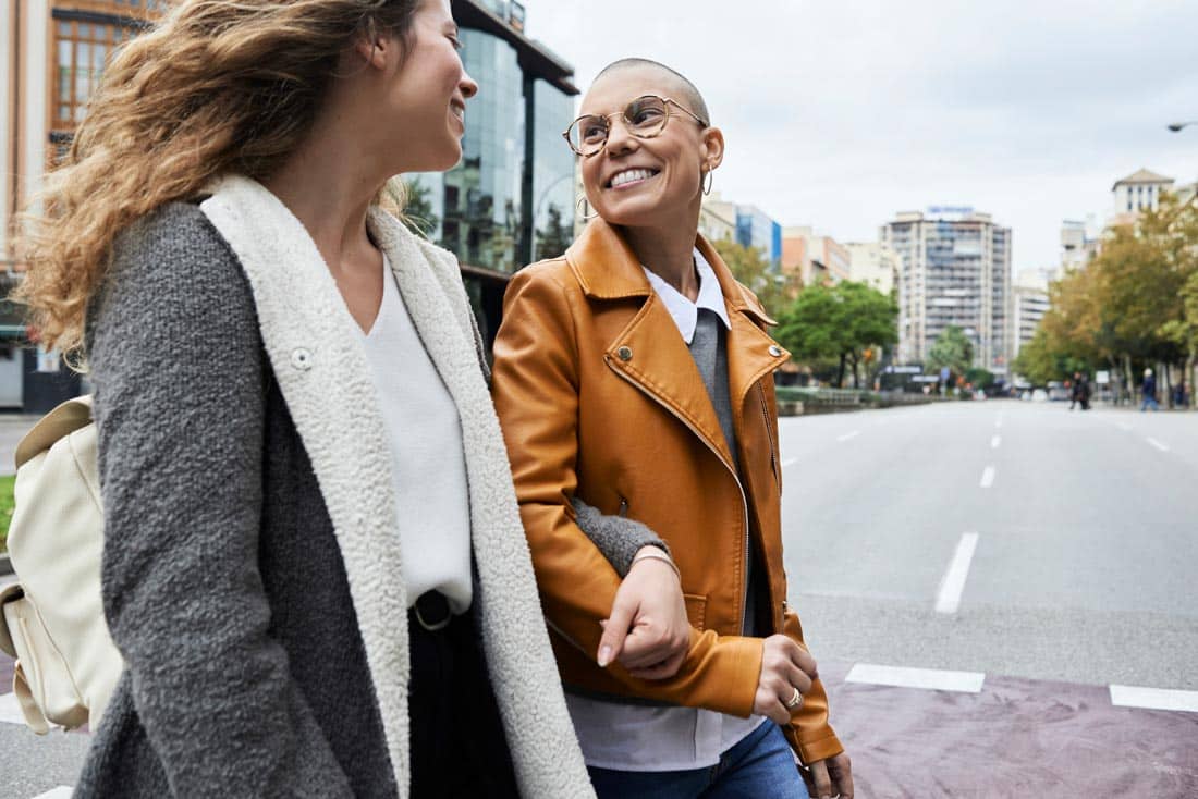 Two women walking arm in arm across a cross walk, personal growth for healthy relationships