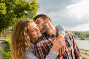 A man and woman embrace and kiss in the sunshine representing emotional safety in relationships