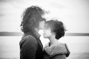 A man kisses a woman forehead on a beach representing how to heal your relationship after an affair