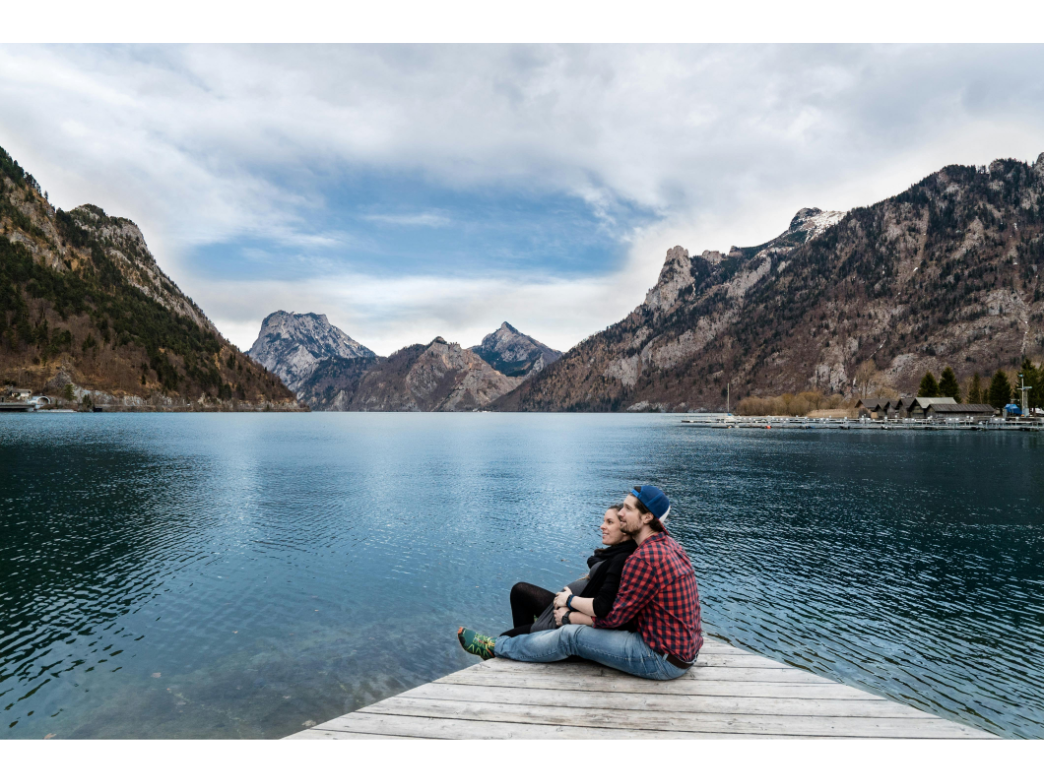 A couple cuddles on a dock looking over a lake representing how to be in love with your partner