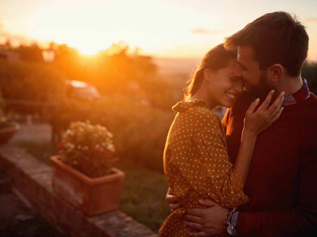 A couple rekindling the romance in their relationship, hugging at sunset.