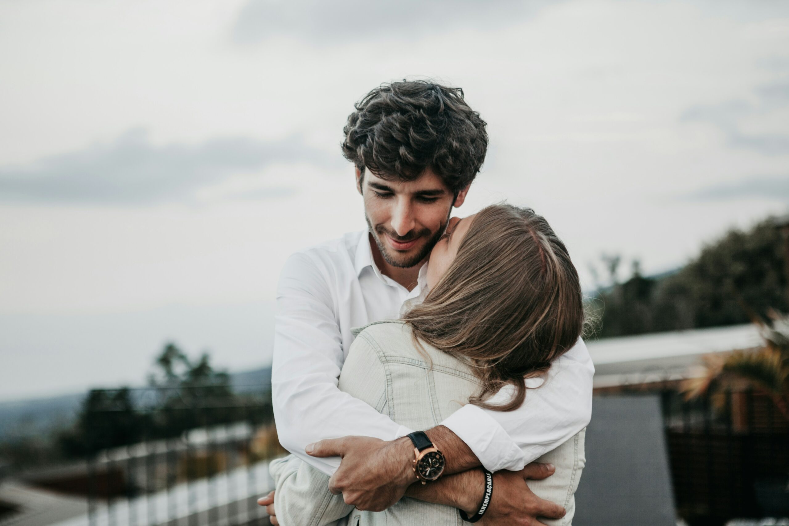 A man and a woman hug on a balcony representing how men feel loved