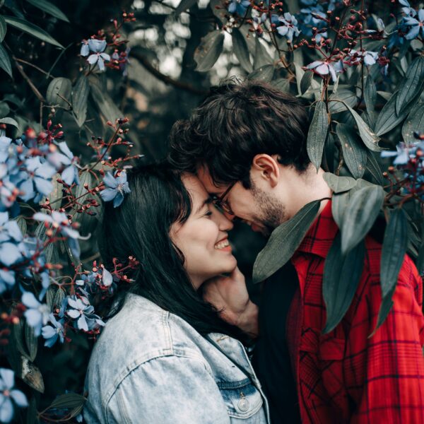 A couple shows nuzzles under some flowering branches, representing how to repair trust in a relationship