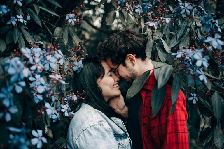 A couple shows nuzzles under some flowering branches, representing how to repair trust in a relationship