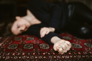 A woman lays on a rug clutching a wedding ring representing how to leave a toxic relationship with dignity