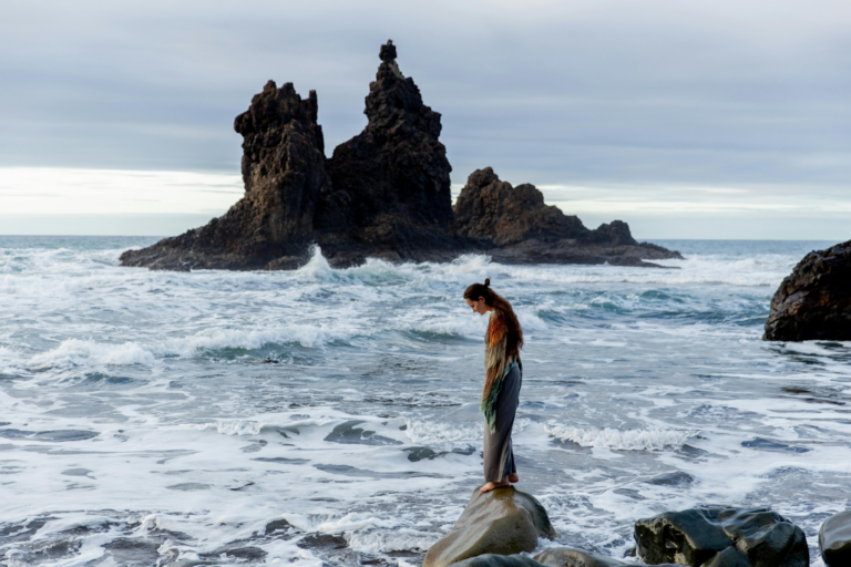 A woman stands on a rock looking out at the sea representing why your breakup was the right choice