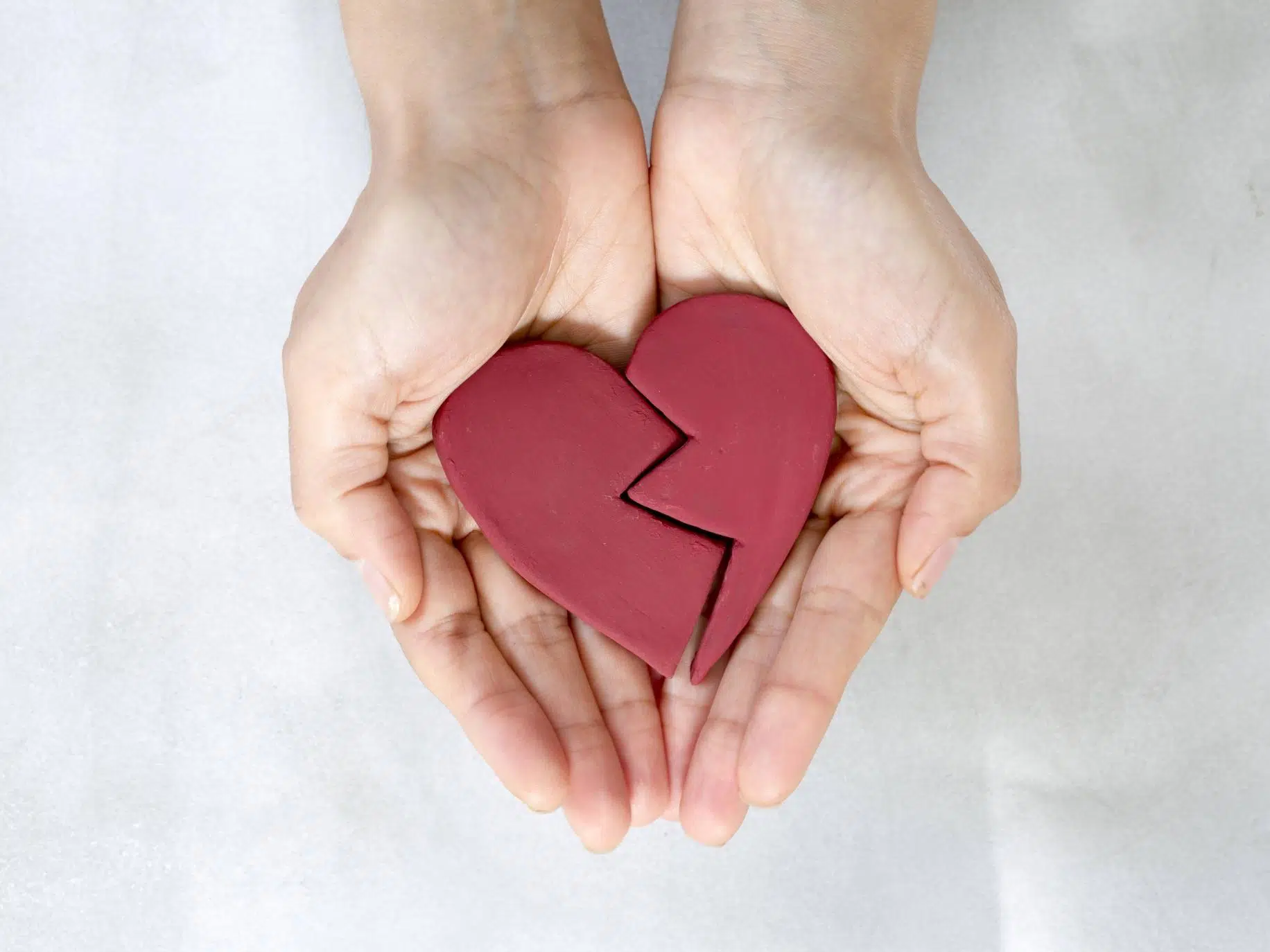 hands holding broken clay heart representing Infidelity Recovery Stages: Healing Your Relationship