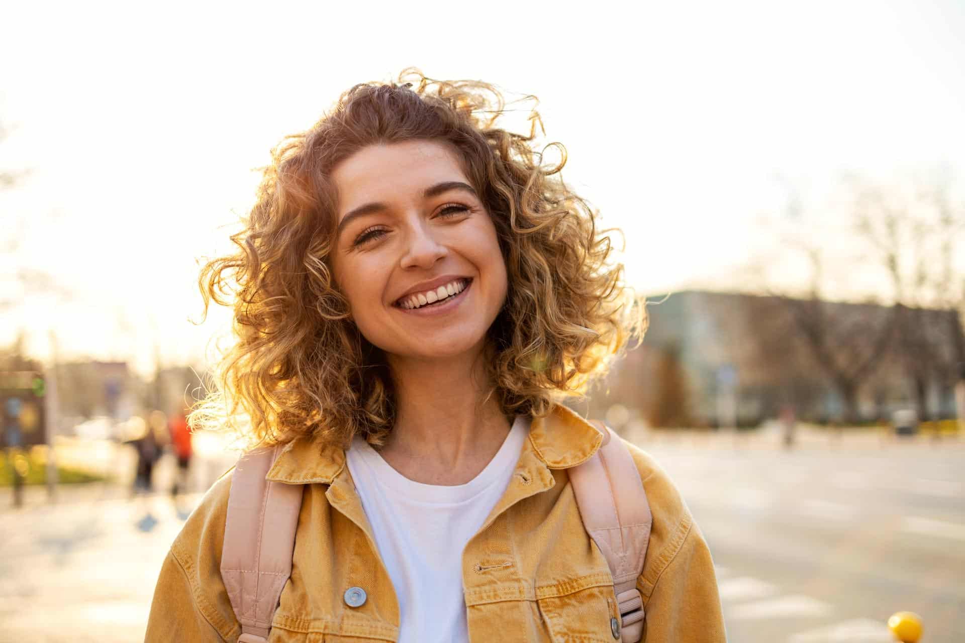 woman smiling at camera, how to transfer bad feelings into authentic happiness