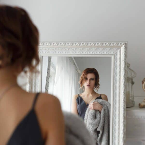 Woman looking in mirror, working on feeling confident
