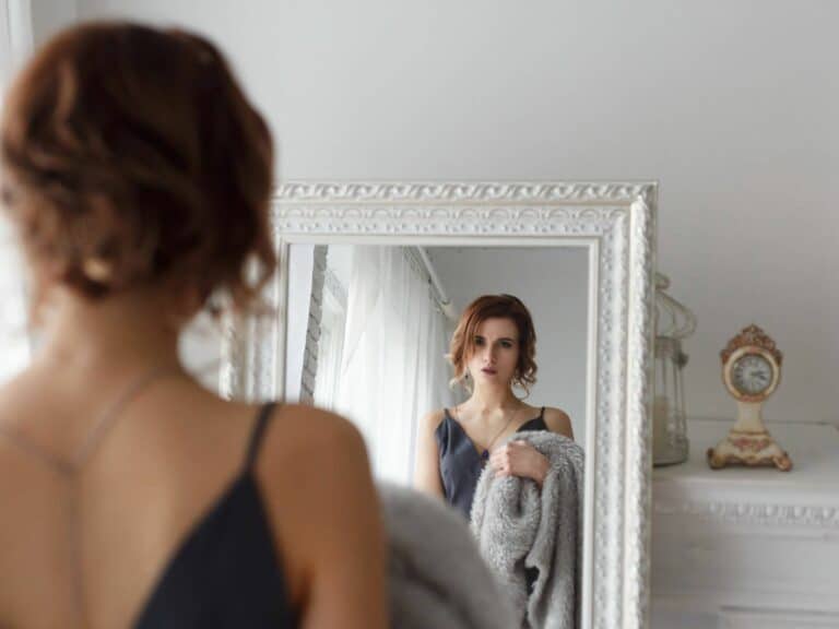 Woman looking in mirror, working on feeling confident