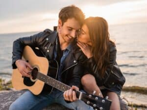 Couple playing guitar together, in love