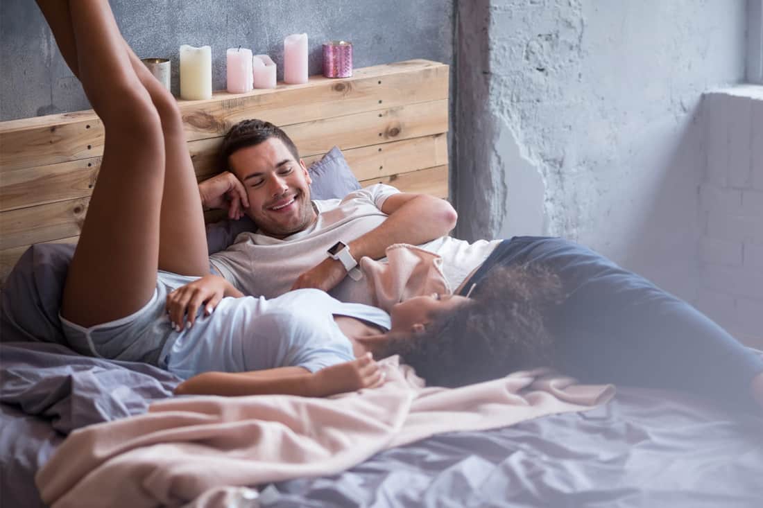 Couple lying on bed together with legs up the wall.