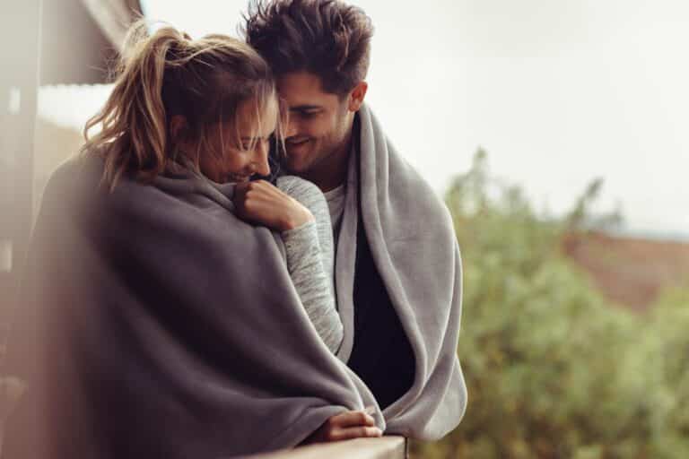 Couple snuggling in blanket.