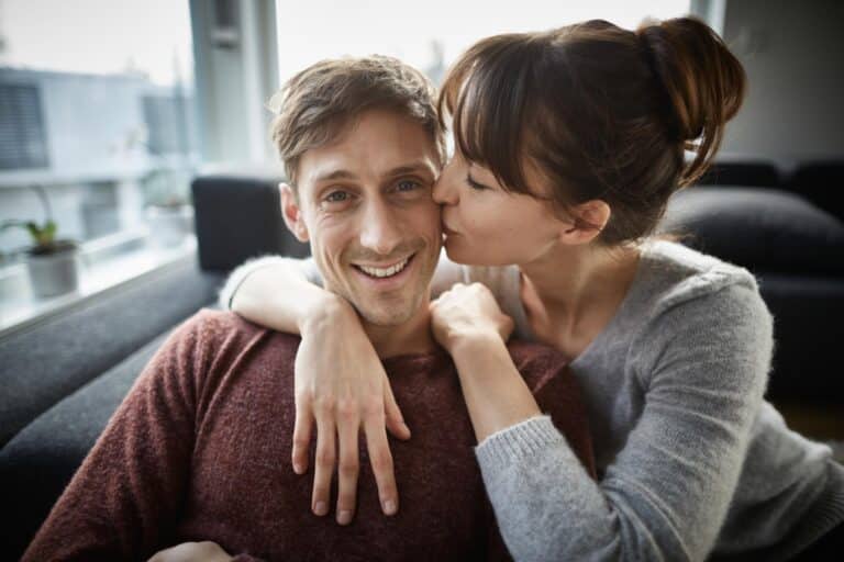 Couple on couch, woman kissing cheek