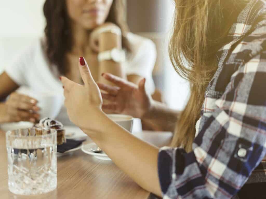 Two women talking at table.