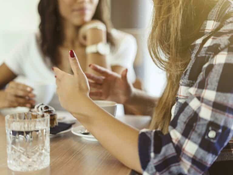 Two women talking at table.
