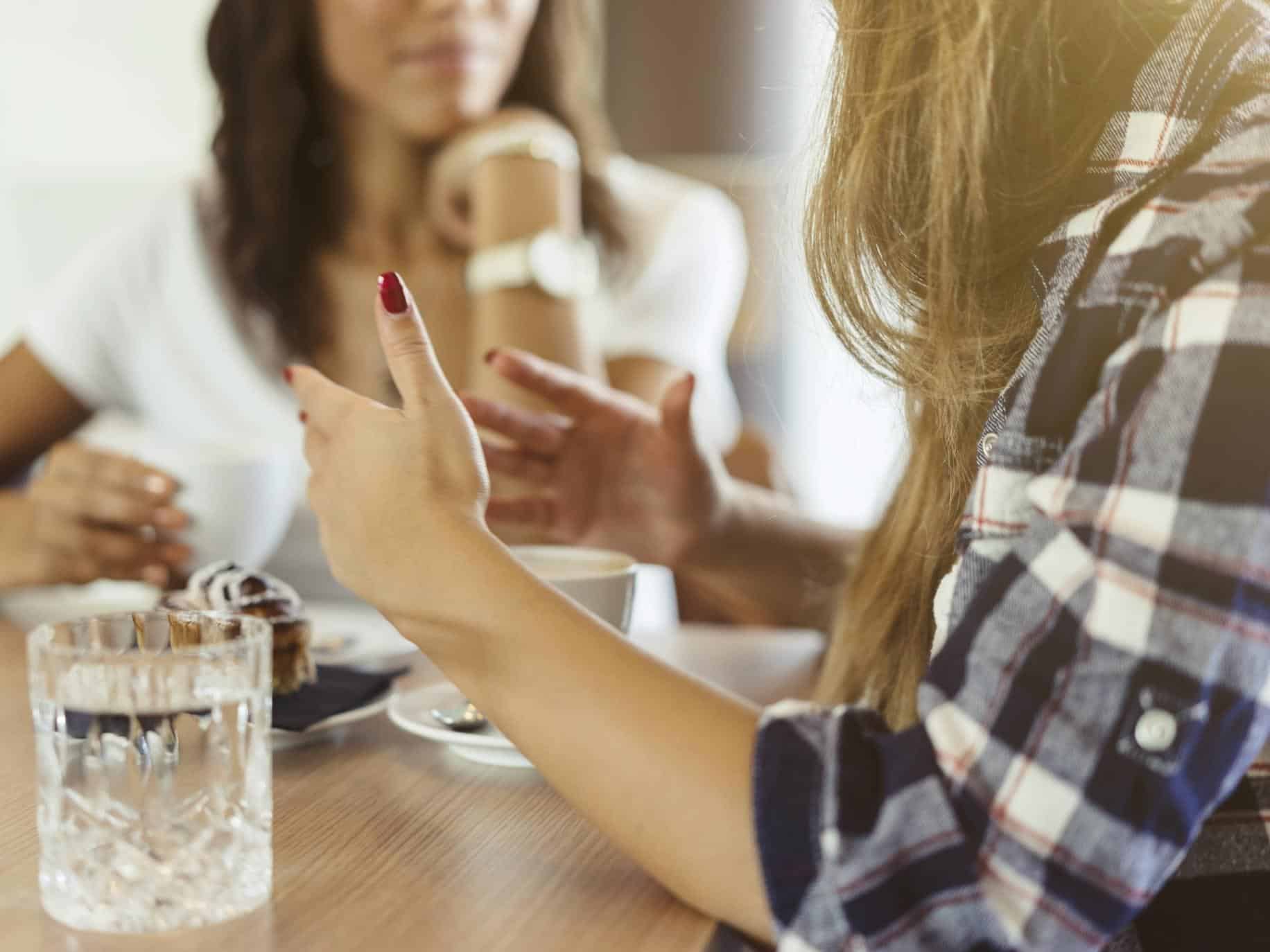 Two women talking at table.